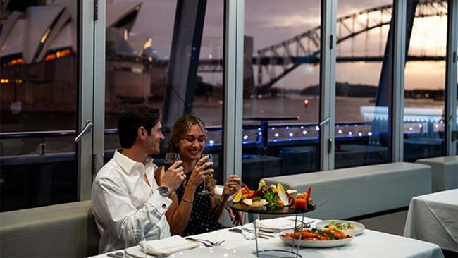 Couple enjoying dinner on the Clearview glass boat cruise with Sydney Harbour views